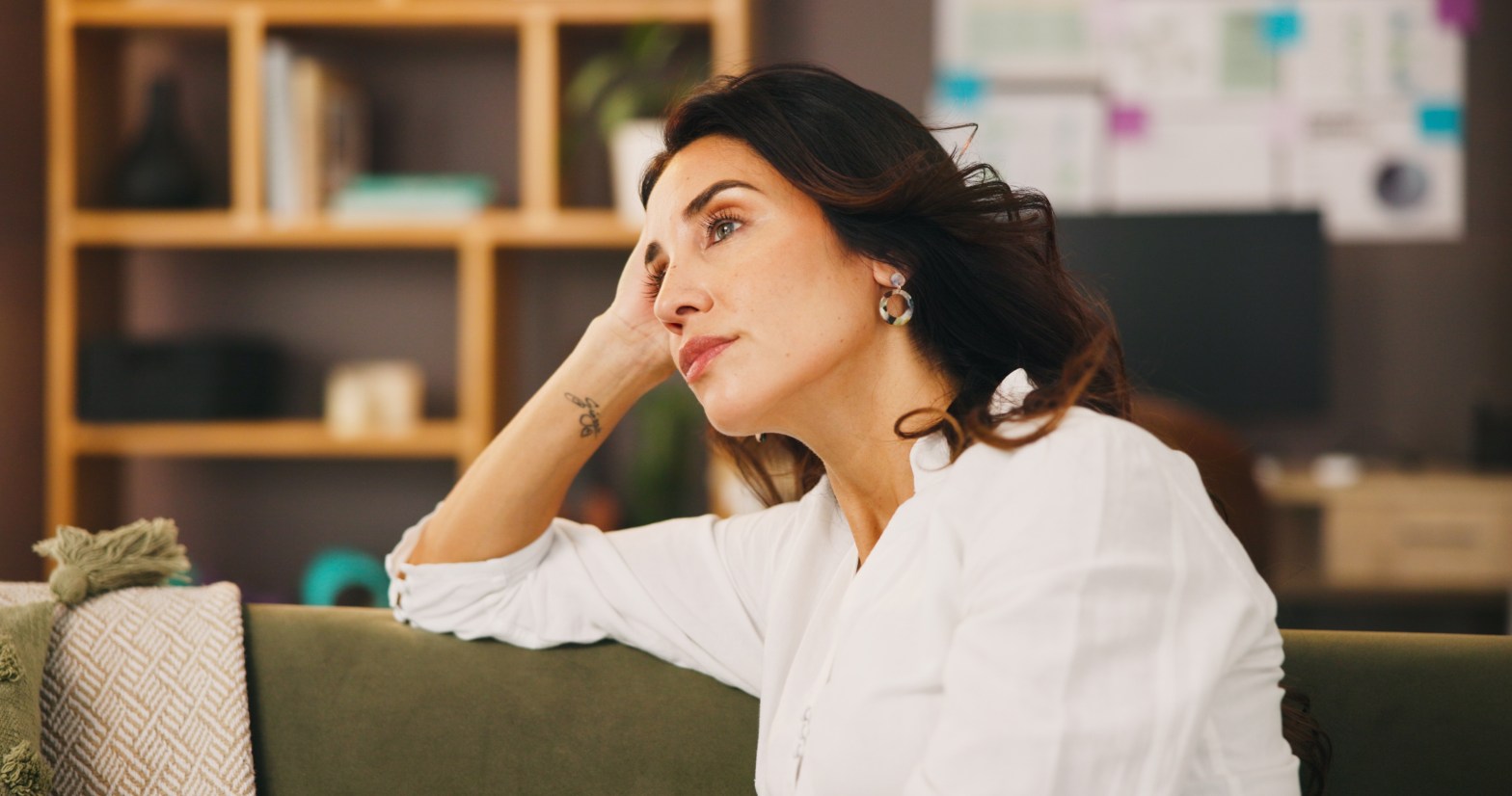 Woman sitting down looking into distance in contemplative thought