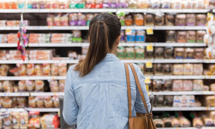 image of woman standing in front of ultra processed food options at grocery store